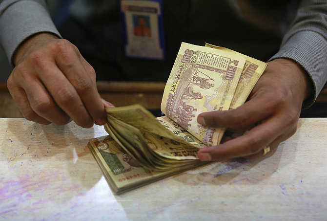 A cashier counts rupee notes inside a bank in Mumbai.