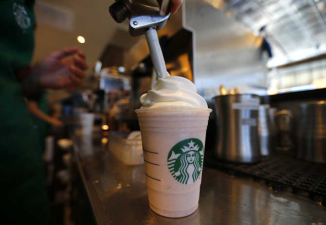 A barista puts whipped cream on a drink at Starbucks coffee shop in Fountain Valley, California.