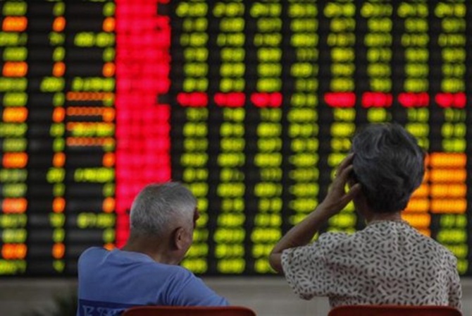 Investors sit in front of an electronic board showing stock information at a brokerage house in Shanghai.