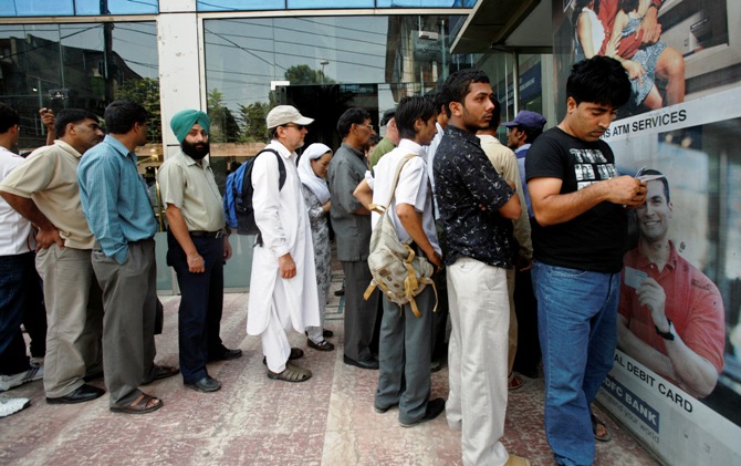 People wait in line outside an ATM to withdraw money in Srinagar.