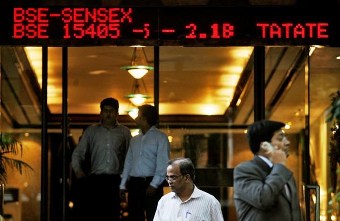 People walk past a digital screen displaying India's benchmark share index in Mumbai.