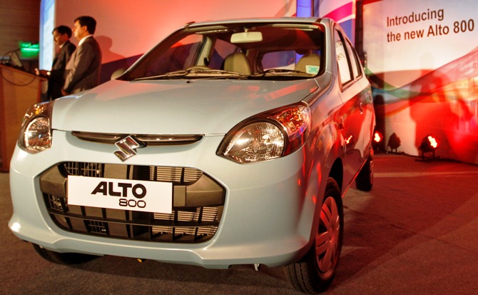 Officials stand next to the newly launched Maruti Suzuki Alto 800 car in Ahmedabad.