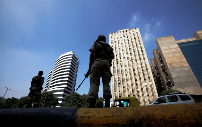 ndian paramilitary soldiers stand guard on a roadside against the backdrop of high-rise buildings in New Delhi.