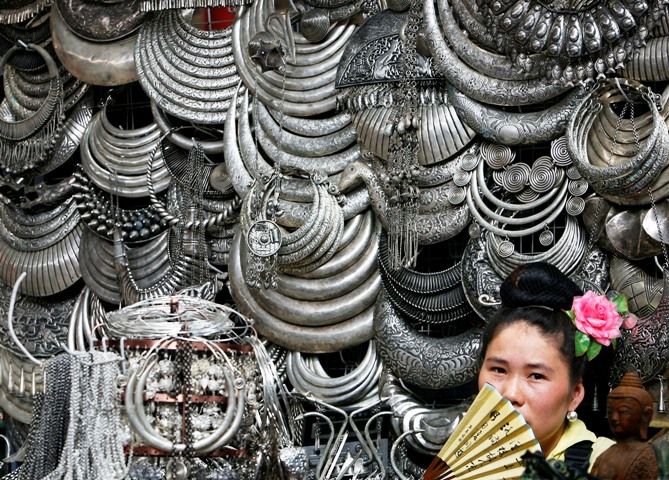 A Chinese vendor selling ethnic silver ornaments waits for customers at a tourist shopping area in Beijing.