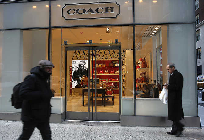 People walk past a Coach store on Madison Avenue in New York, United States.