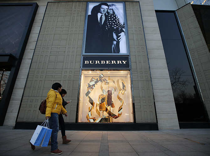 People walk past the window display of a Burberry store in Beijing, China.