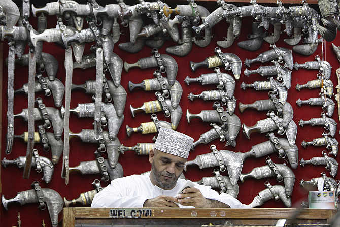 A man sits in front of a display of jambiyas (traditional daggers) in Mattrah Souq, the oldest market in Oman, in the capital Muscat.