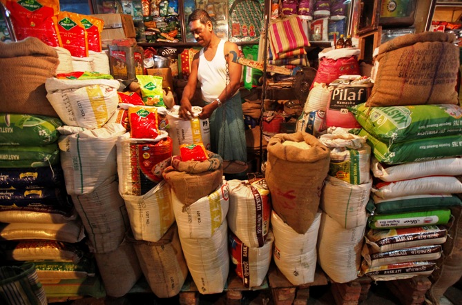 The owner of a 'Kirana' or mom-and-pop grocery store arranges a rice sack in Kolkata. 