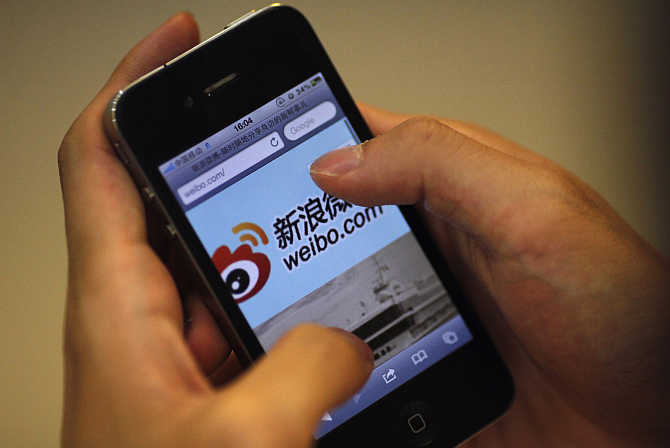A man holds an iPhone as he visits Sina's Weibo microblogging site in Shanghai.