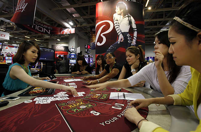 Attendants working for US slot machine maker Bally Technologies learn a poker game before introducing it to visitors at Gaming Expo Asia in Macau.