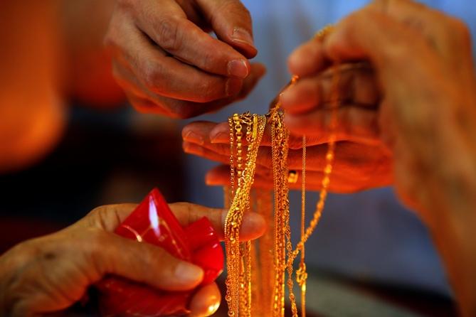 A salesman holds gold to sell to a customer in a gold shop.