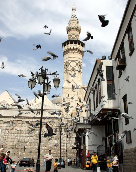 Pigeons fly in front of the historical Umayyad mosque in old Damascus city.