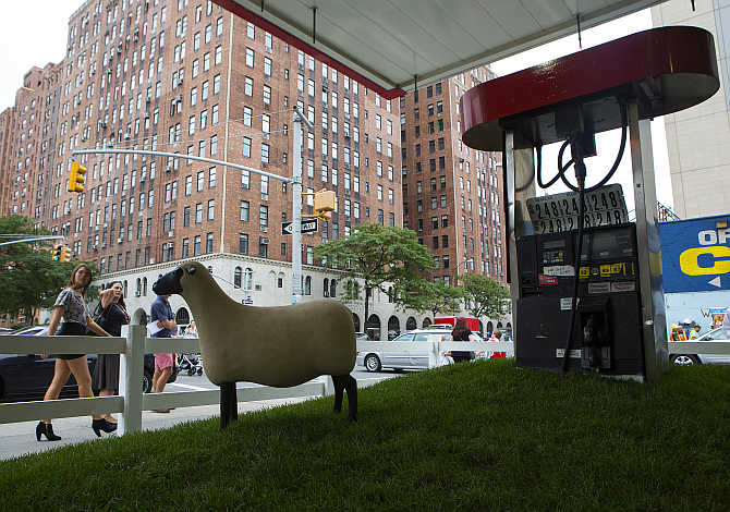 People walk by 'Sheep Station' in the Chelsea neighbourhood of New York. The piece is an art installation at a former petrol pump by Francois-Xavier Lalanne.