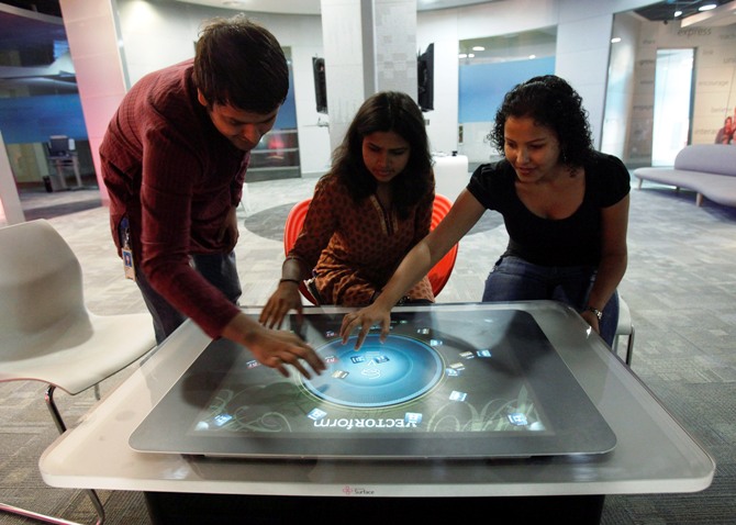 Employees demonstrate the use of the newly-designed prototype of a touch-sensitive table at Microsoft India's Development Center in the Gachibowli IT district in Hyderabad.
