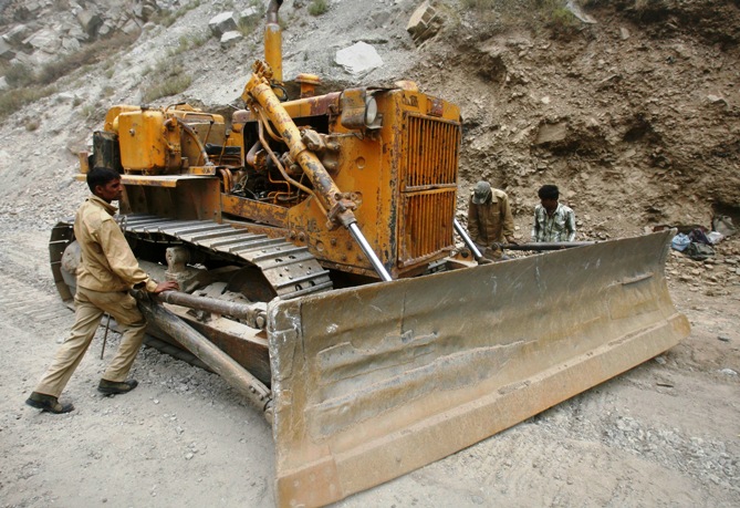 Labourers employed by the Indian army, adjust a bulldozer blade on India's Tezpur-Tawang highway which runs to the Chinese border in China.
