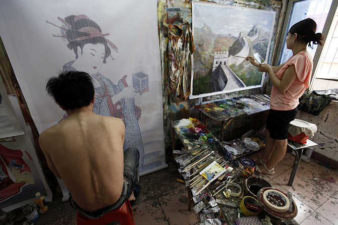 Painters work on oil paintings in a studio at Dafen Oil Painting Village, in Shenzhen, South China's Guangdong province.