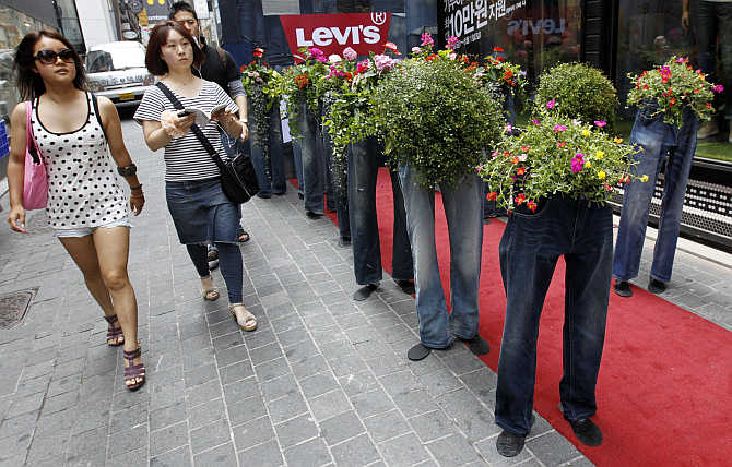People walk past flowerpots made of old jeans during a recycling campaign at the Myeongdong shopping district in Seoul, South Korea.