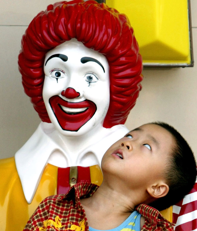 A Chinese boy stares up at a statue of Ronald McDonald in front of a McDonald's Restaurant in Beijing.