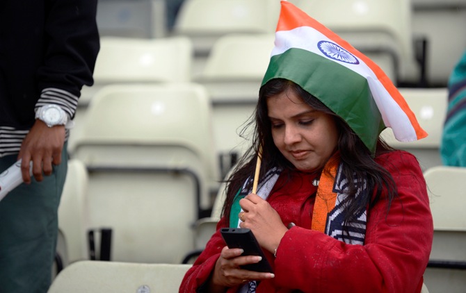 A spectator sits in the rain sheltering under a small flag during the ICC Champions Trophy group B match between India and Pakistan at Edgbaston cricket ground, Birmingham June 15, 2013.