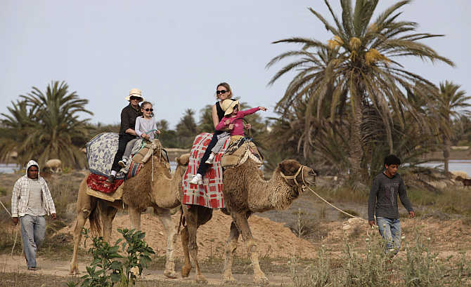 Tourists ride camels on the island of Djerba, Tunisia.