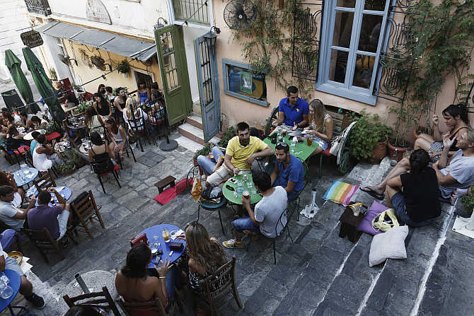 People sit at a cafe at the tourist district of Plaka in central Athens, Greece.