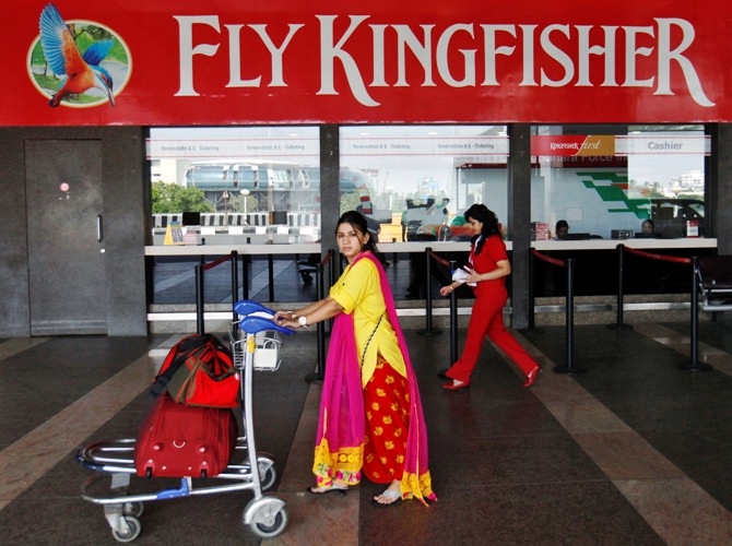 A passenger walks with her luggage in front of a Kingfisher Airlines reservation office at the domestic airport in Mumbai.