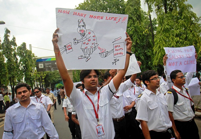 An employee holds a poster with an illustration of Vijay Mallya, chairman and chief executive of Kingfisher Airlines, during a protest march against the company in Mumbai October 5, 2012.