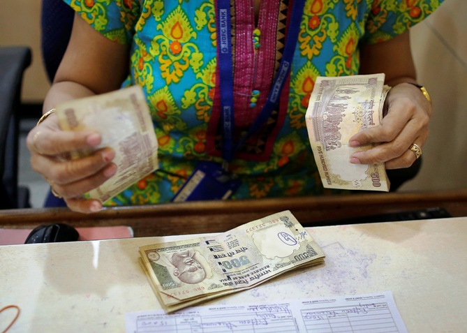 A cashier counts Indian rupee currency notes inside a bank in Mumbai December 6, 2013.