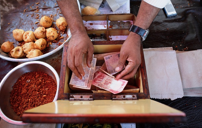 A streetside restaurant owner keeps money received from a customer in Mumbai.