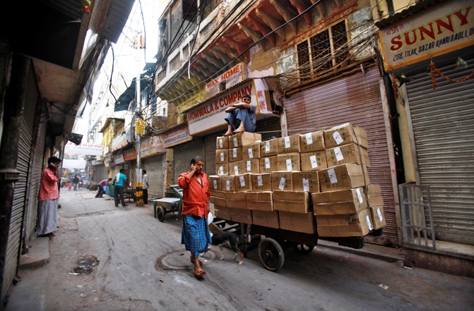 A worker sits on top of a handcart loaded with goods at a wholesale grocery market in the old quarters of Delhi.