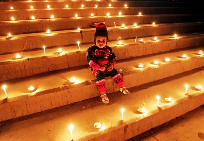 A girl sits on the staircase decorated with lamps and candles on the occasion of Diwali festival in Allahabad.