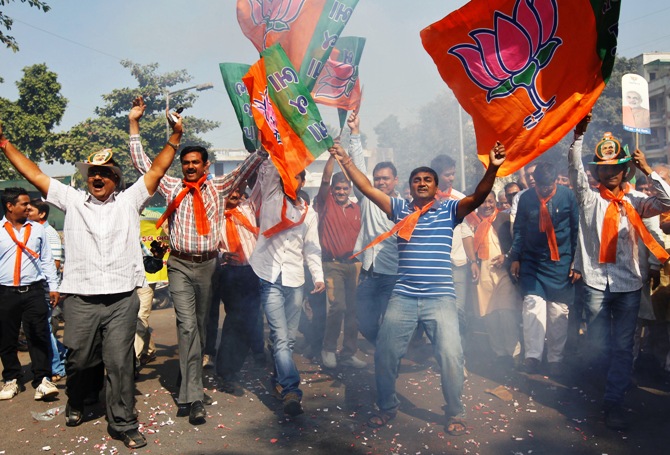 Supporters of Bharatiya Janata Party wave party flags as they celebrate outside the party's headquarters in Ahmedabad.
