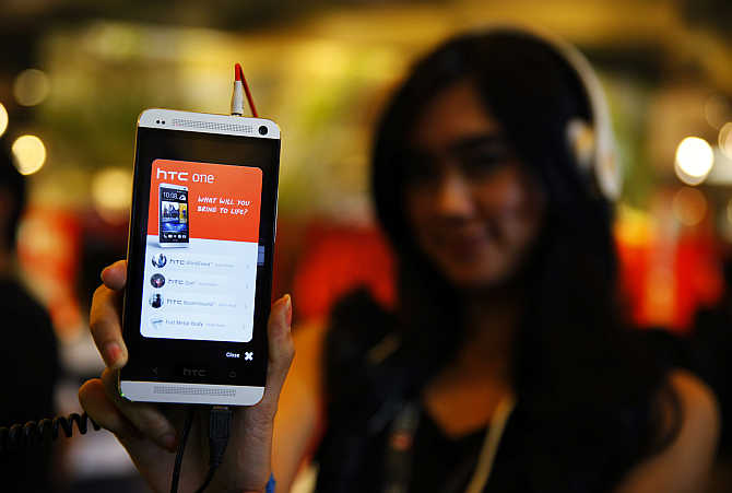 A sales girl displays the HTC One mobile phone at Taman Anggrek Mall in Jakarta, Indonesia.