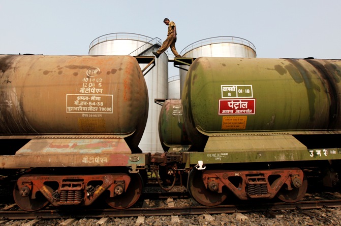 A worker walks atop a tanker wagon to check the freight level at an oil terminal on the outskirts of Kolkata.