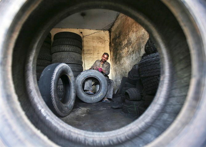 A worker retreads a used rubber tyre at a workshop on the outskirts of Jammu.