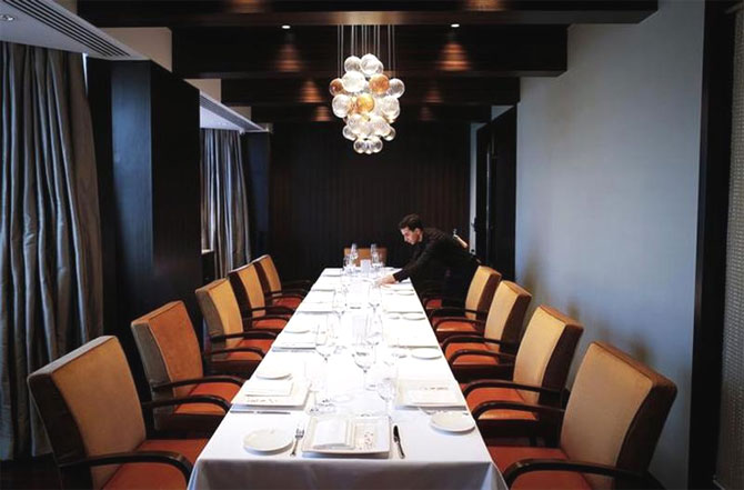 An employee of Le Cirque Signature restaurant prepares a table inside a private dining room in Mumbai.