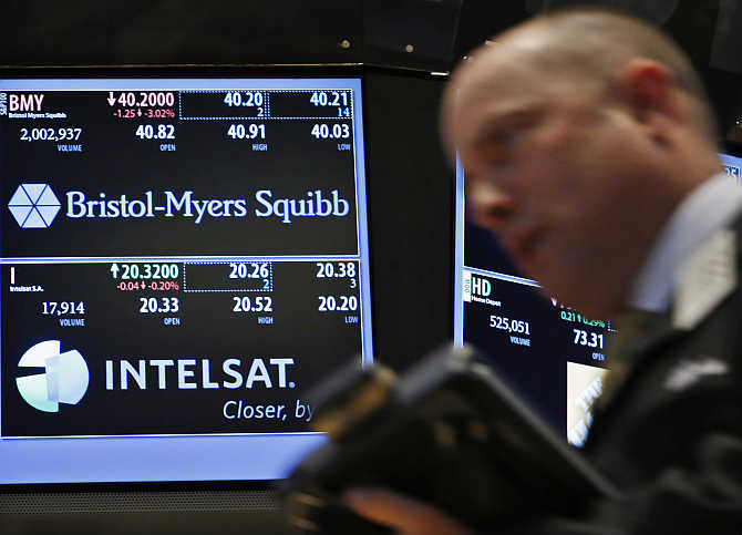 A trader passes by a screen displaying the tickers symbols for Bristol-Myers Squibb on the floor at the New York Stock Exchange.