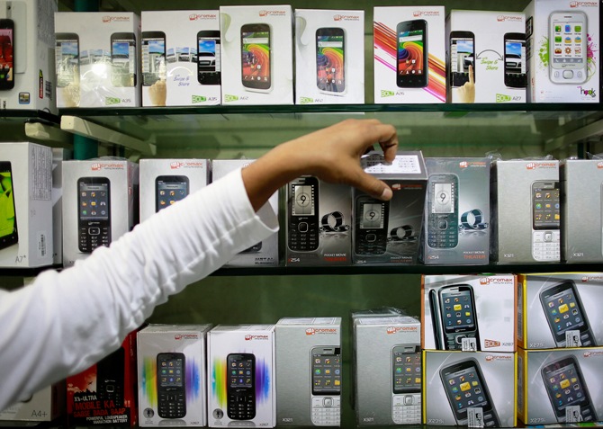 An employee takes out a Micromax mobile phone from the display at a mobile store in Mumbai.