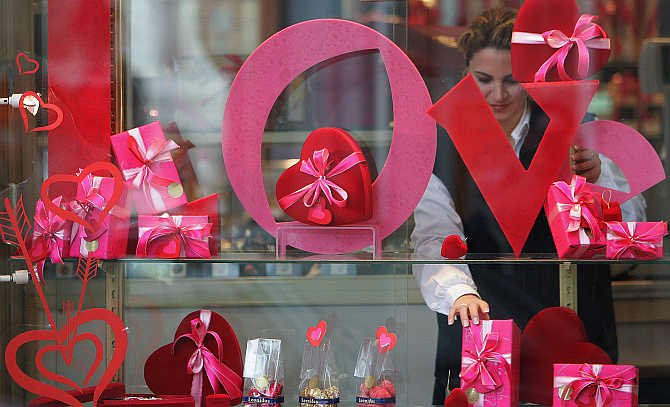 A vendor adjusts decorative red hearts and praline boxes behind the window of a Belgian chocolate shop in Brussels.