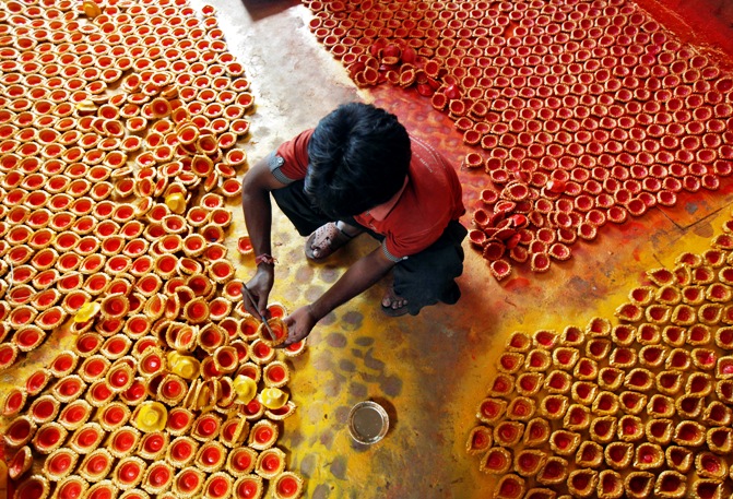 A worker paints earthen lamps in Kolkata.