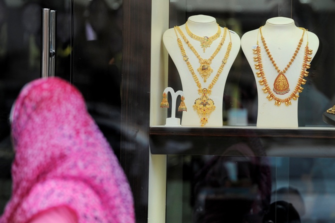 A woman walks past a window display for gold jewellery at Hamdan Street.