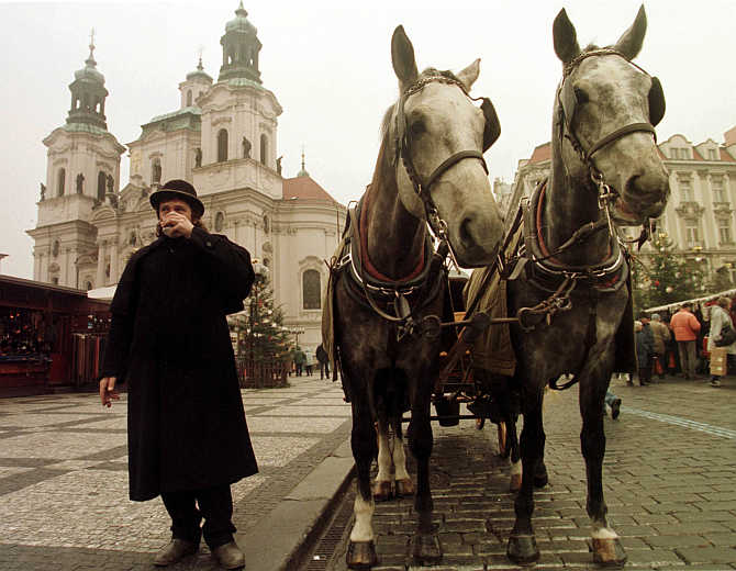 A coachman keeps himself warm by sipping a hot cup of coffee in central Prague's Old Town Square, the Czech Republic.