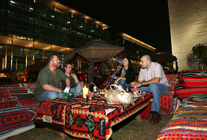 People smoke water pipes and drink coffee at Ziara Ramadan tent in Dubai, United Arab Emirates.