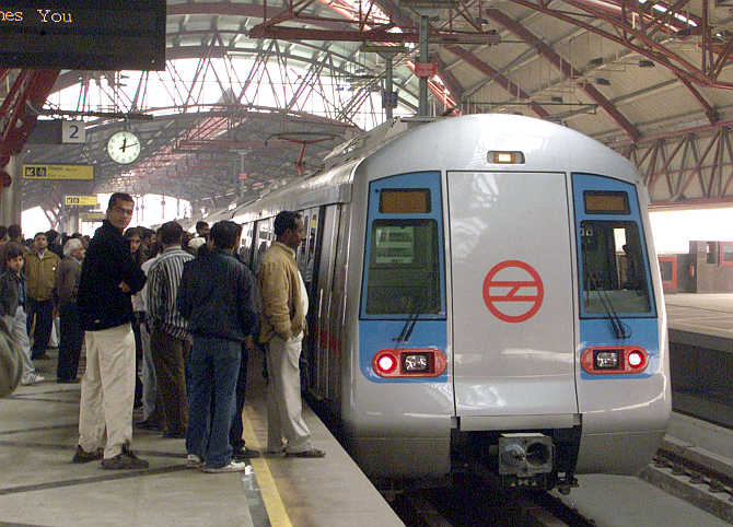 Commuters wait to board a Metro train in New Delhi.
