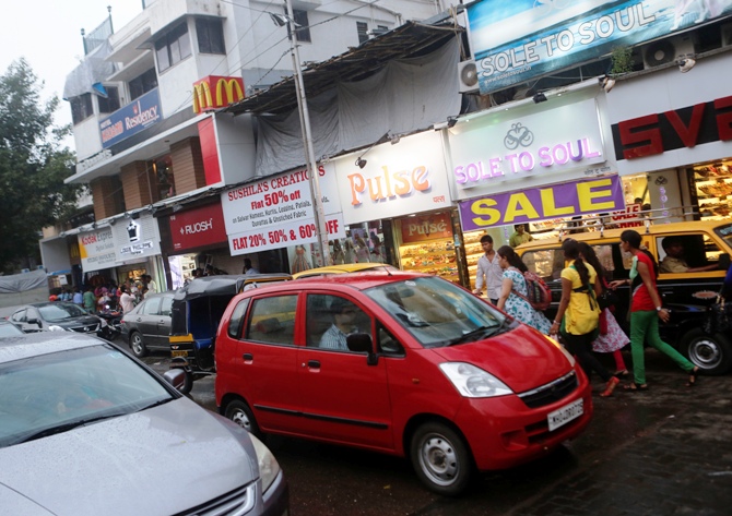 Vehicles drive past stores on a street in Mumbai.