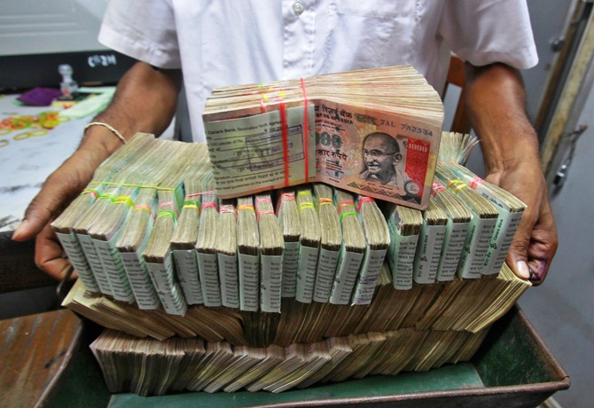 An employee poses with the bundles of Indian rupee notes inside a bank in Agartala.