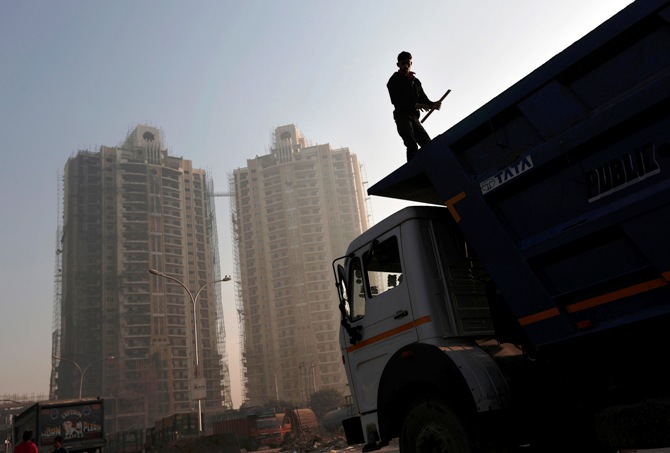 A labourer stands on a truck carrying construction materials at a construction site of residential buildings in Noida on the outskirts of New Delhi.