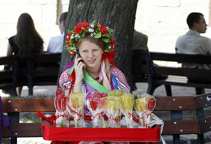 A street vendor, dressed in national costume, talks on a mobile phone as she sells candy in downtown Lviv in western Ukraine.