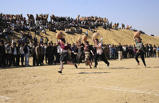 Tourists carry earthen pitchers on their heads as they participate in Matka Race competition at Ladera village near Bikaner in Rajasthan.