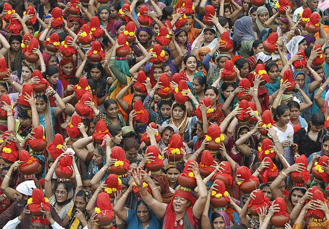 Women carry earthen water pots as they take part in a Jhulelal Chaliha procession in Ahmedabad.